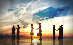Business people shaking hands in airport with world map