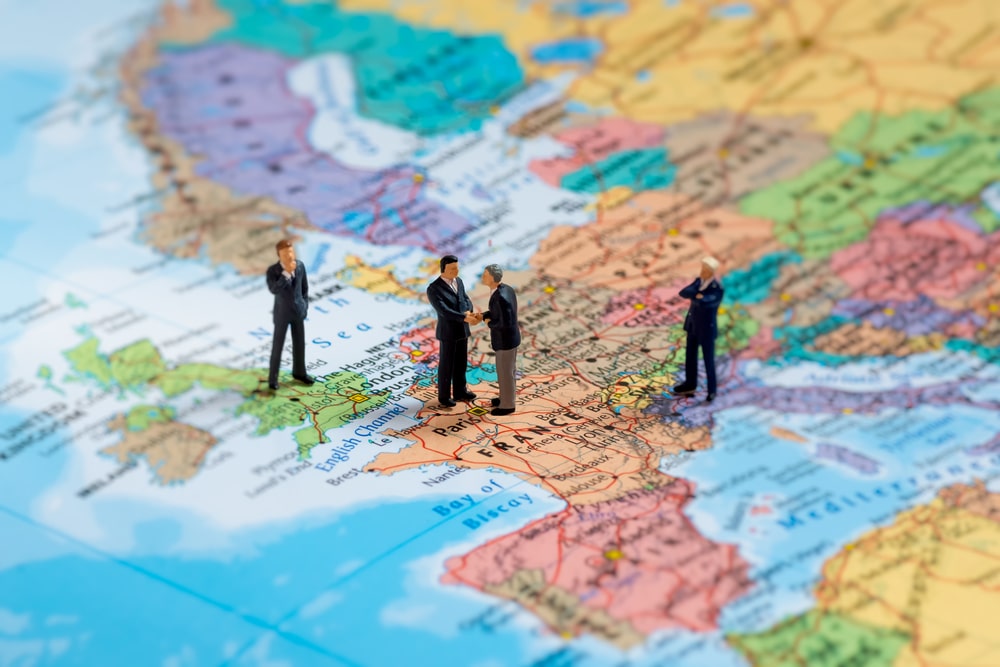 Business people figurines shaking hands on map of Europe